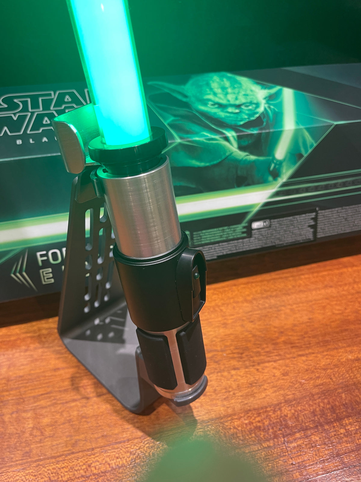 Réplica do sabre de luz de Yoda iluminado e colocado no suporte de exposição